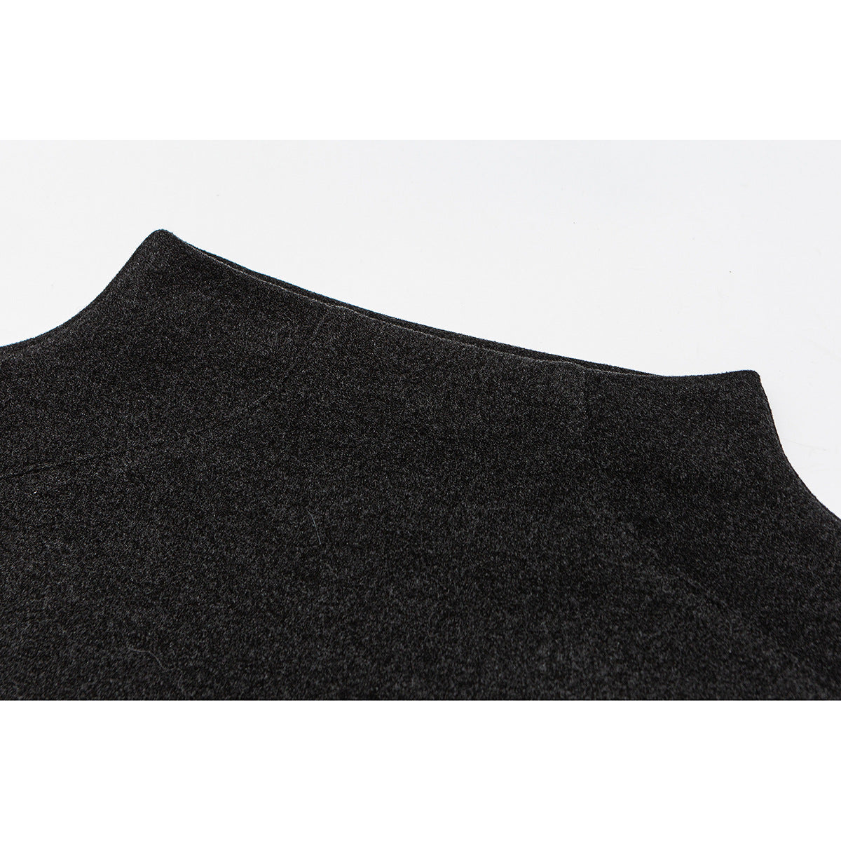 Close-up of the curved edge of a charcoal top against a white background.