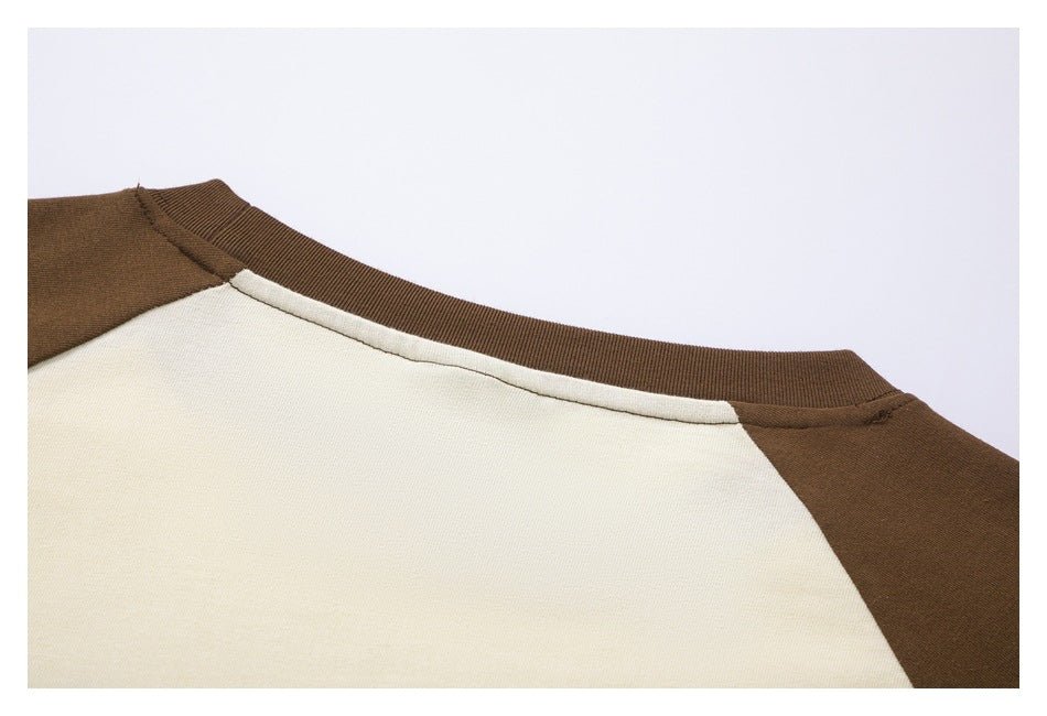 Close-up of an ivory shirt neckline with a brown ribbed collar and brown raglan shoulder panels.