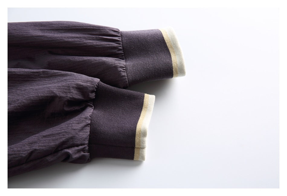 Close-up of two dark plum sleeve cuffs with cream and pale yellow trim.