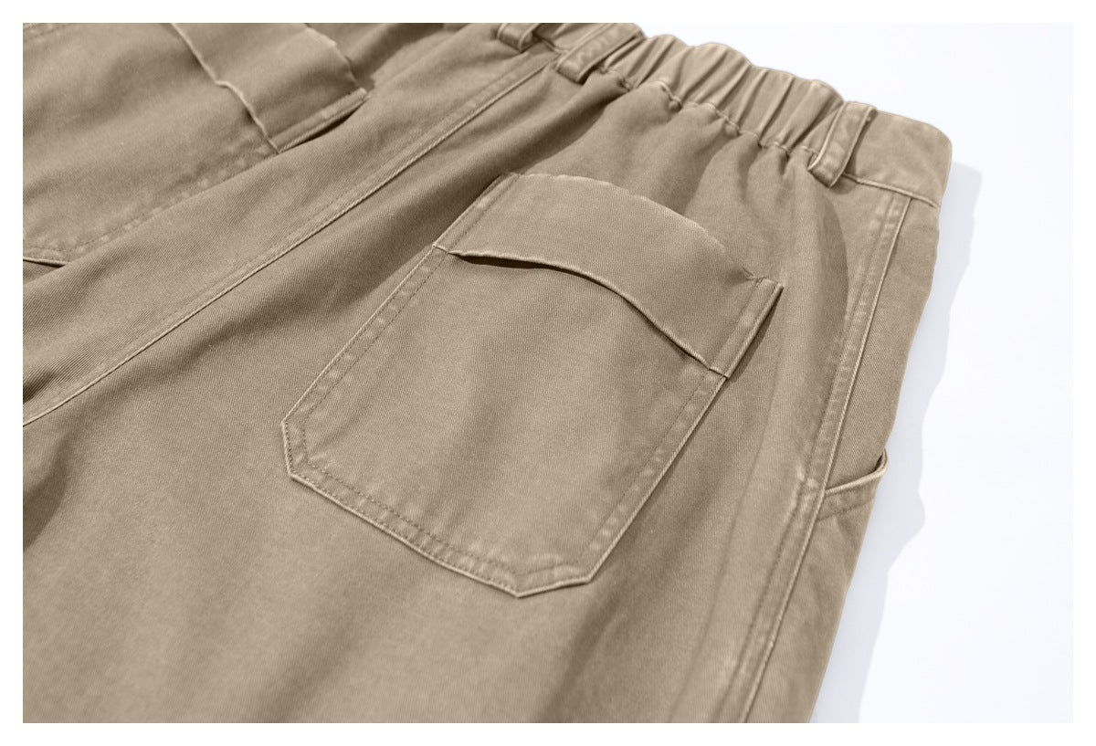Close-up of tan trousers showing an elastic waistband and a flap pocket.