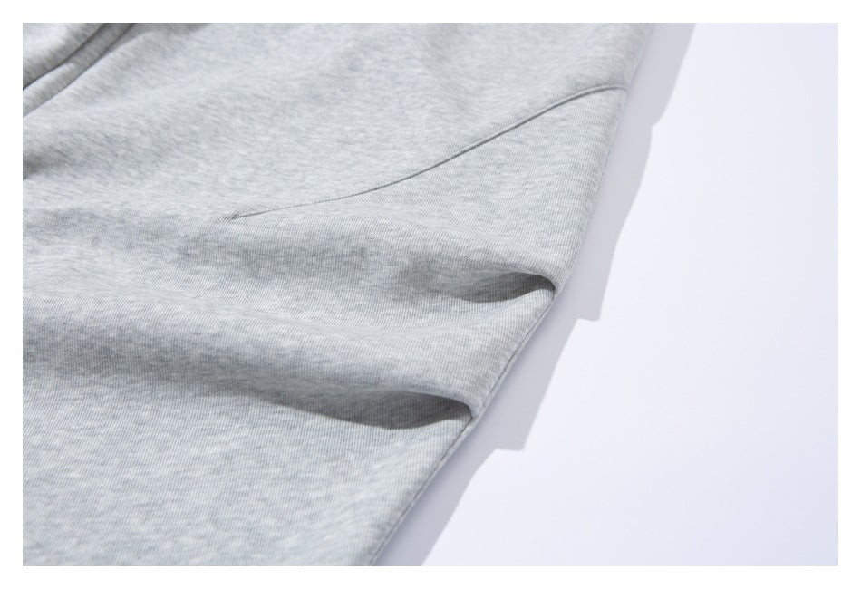 Close-up of light gray sweatpants fabric and a curved stitched seam near the side.