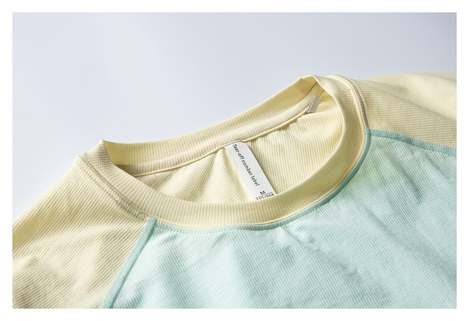 Close-up of the mint and pale yellow top's crew neckline, shoulder seam, and attached inner label.