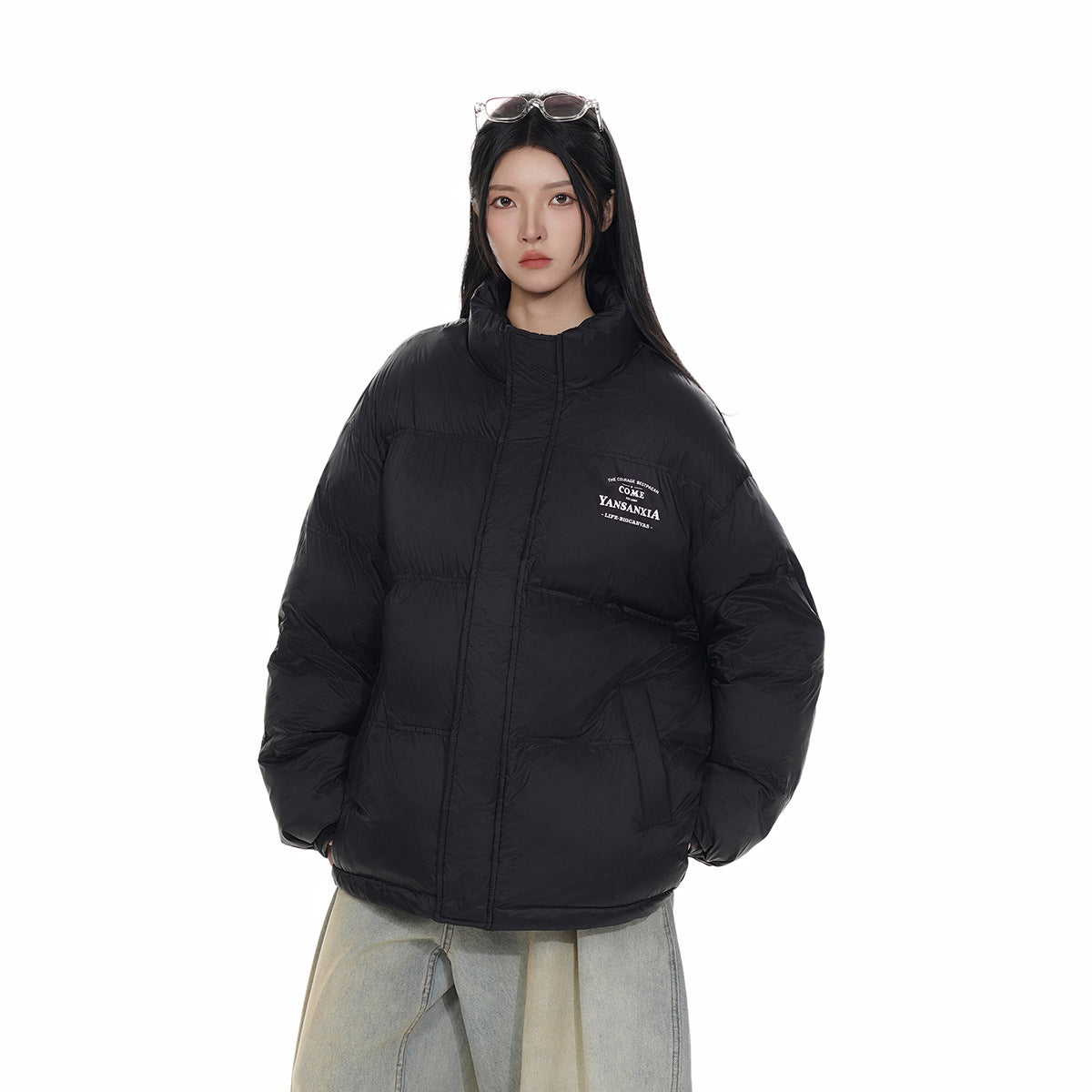 Closer front view of a model wearing a black high-collar quilted puffer jacket and light-wash jeans.