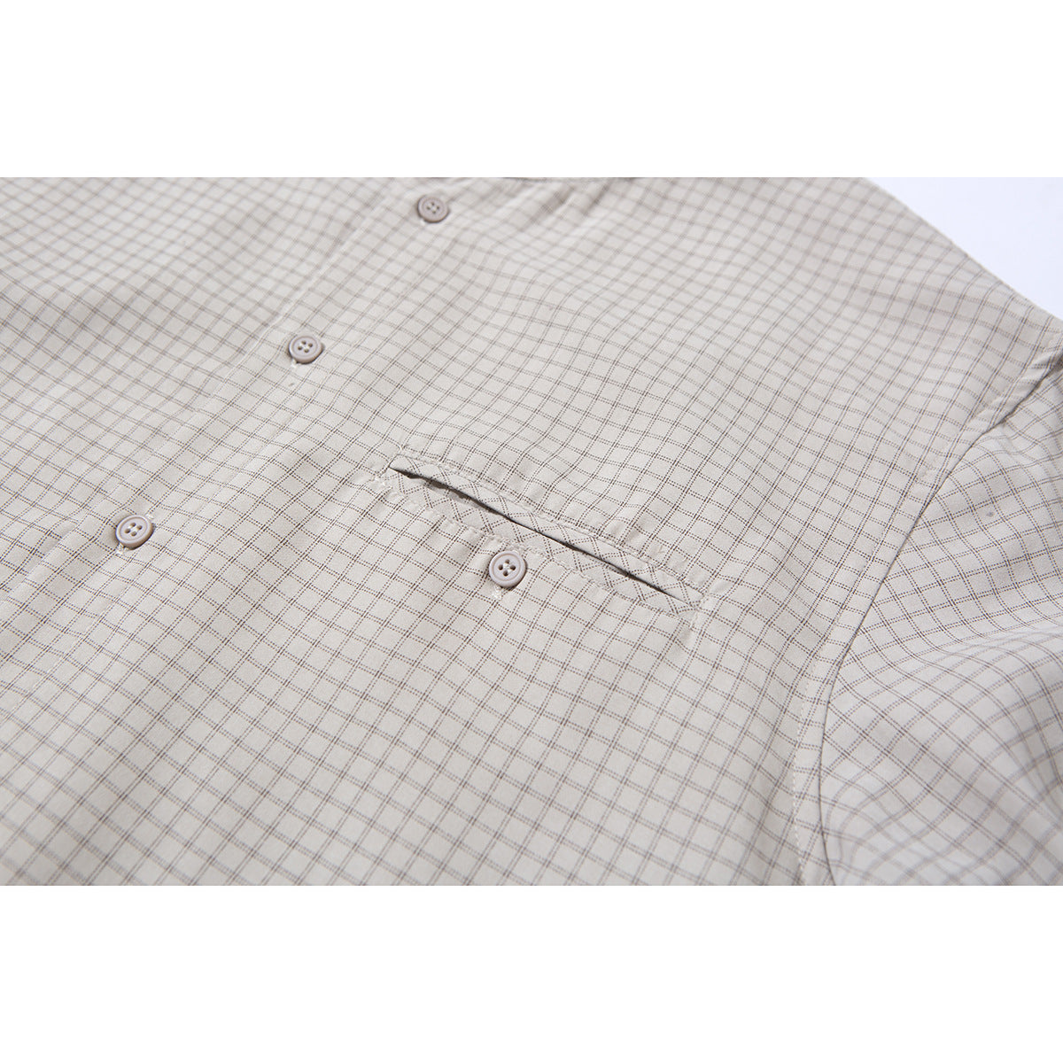 Close-up of a light beige checked shirt chest pocket and front buttons.