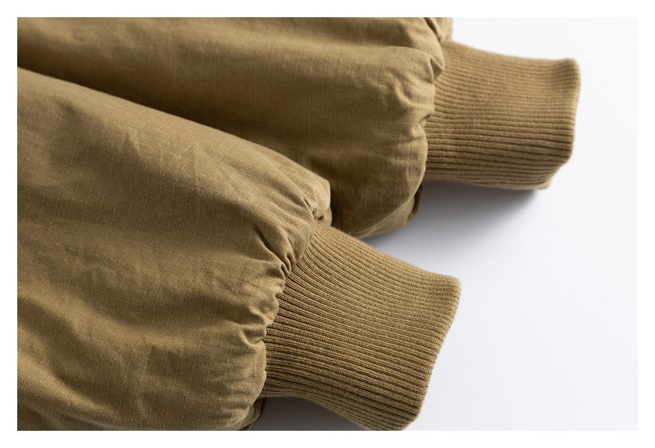 Close-up of two olive-brown jacket sleeves with ribbed knit cuffs.