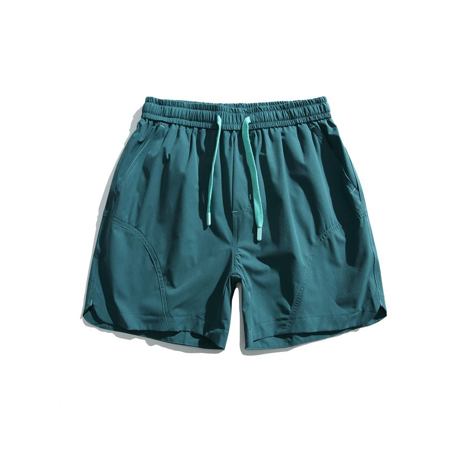 Dark teal green drawstring shorts with mint drawstring, side pockets and curved seam panels, flat front view