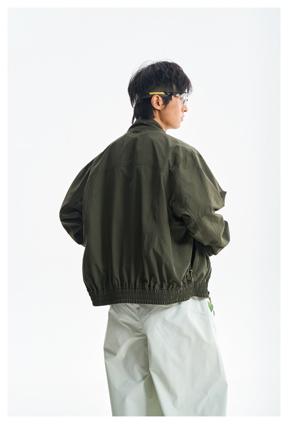 Model wearing an olive green jacket, shown from the back with an elasticated hem and cuffs.