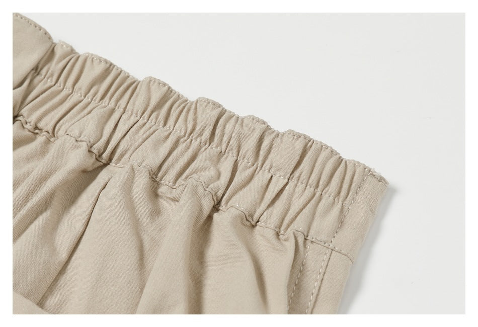 Close-up of the gathered elastic waistband on beige trousers.