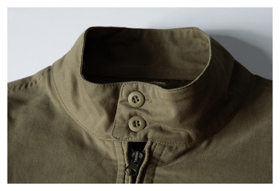 Close-up of an olive jacket's stand collar with two buttons and a front zipper.