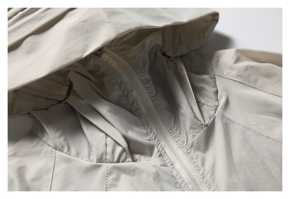 Close-up of the light beige jacket's hood lining, front zipper, and textured shoulder panel.
