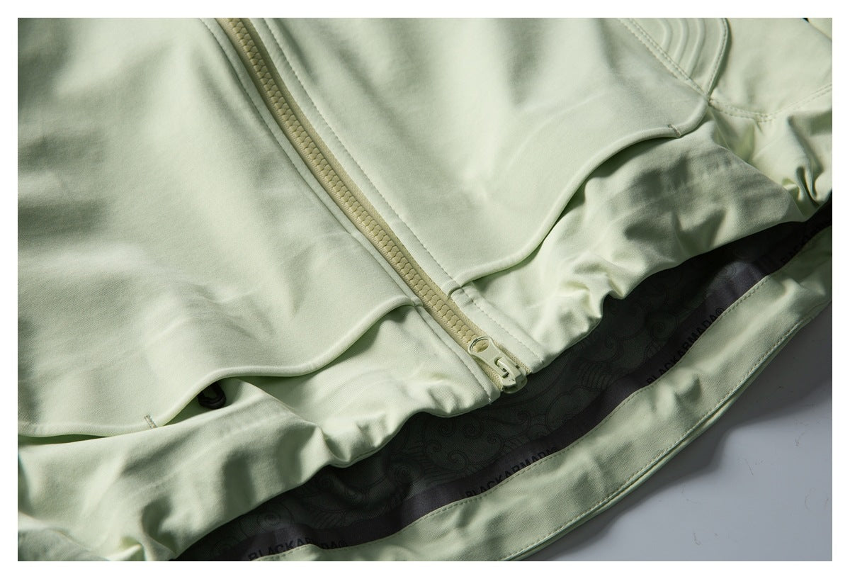 Close-up of the pale sage-green jacket's front zipper, hem, and dark patterned inner lining.