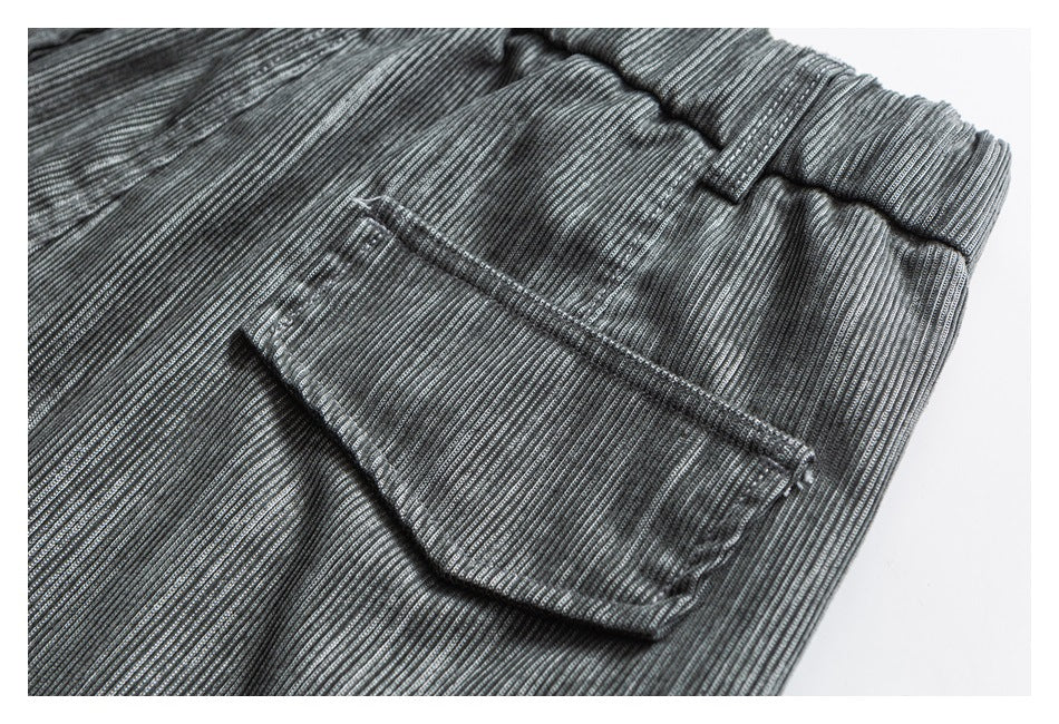 Close-up of a back pocket and elastic waistband on gray striped trousers.