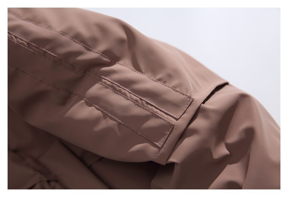 Close-up of a dusty mauve jacket sleeve with a stitched adjustable strap and folded cuff detail.