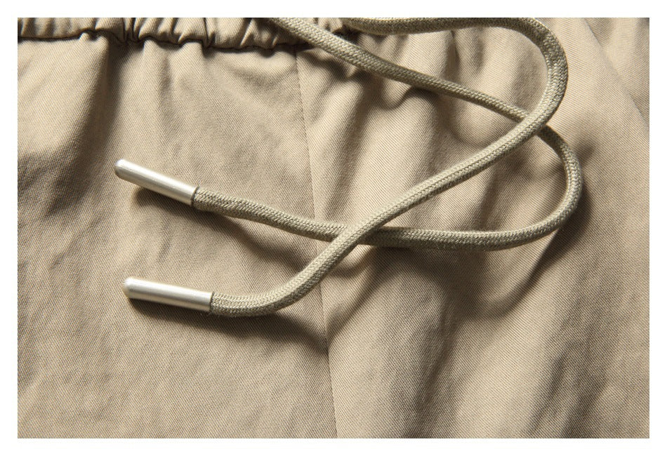 Close-up of khaki shorts with a braided drawstring and metal tips at the elastic waist.