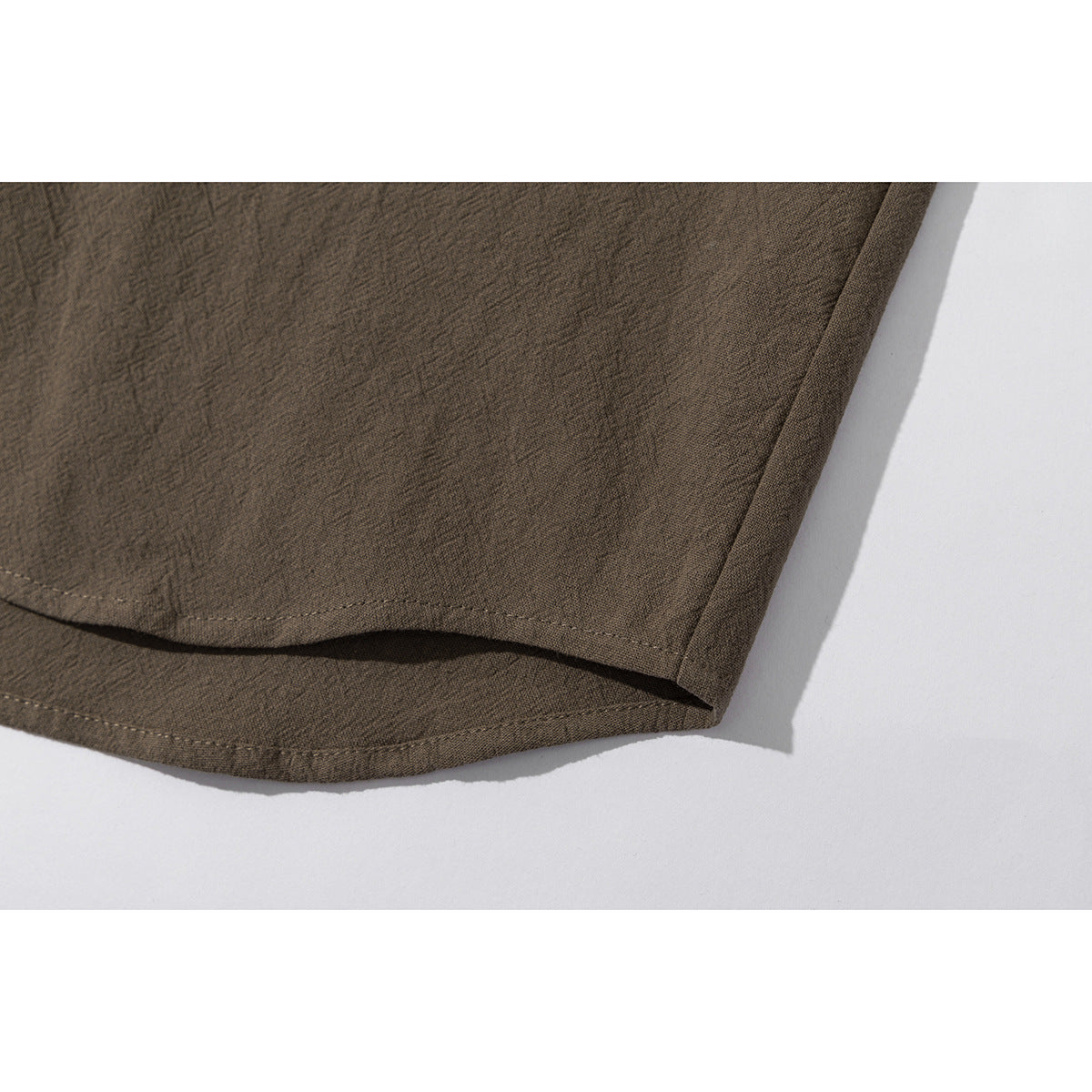 Close-up of the curved hem and side seam of a brown shirt.