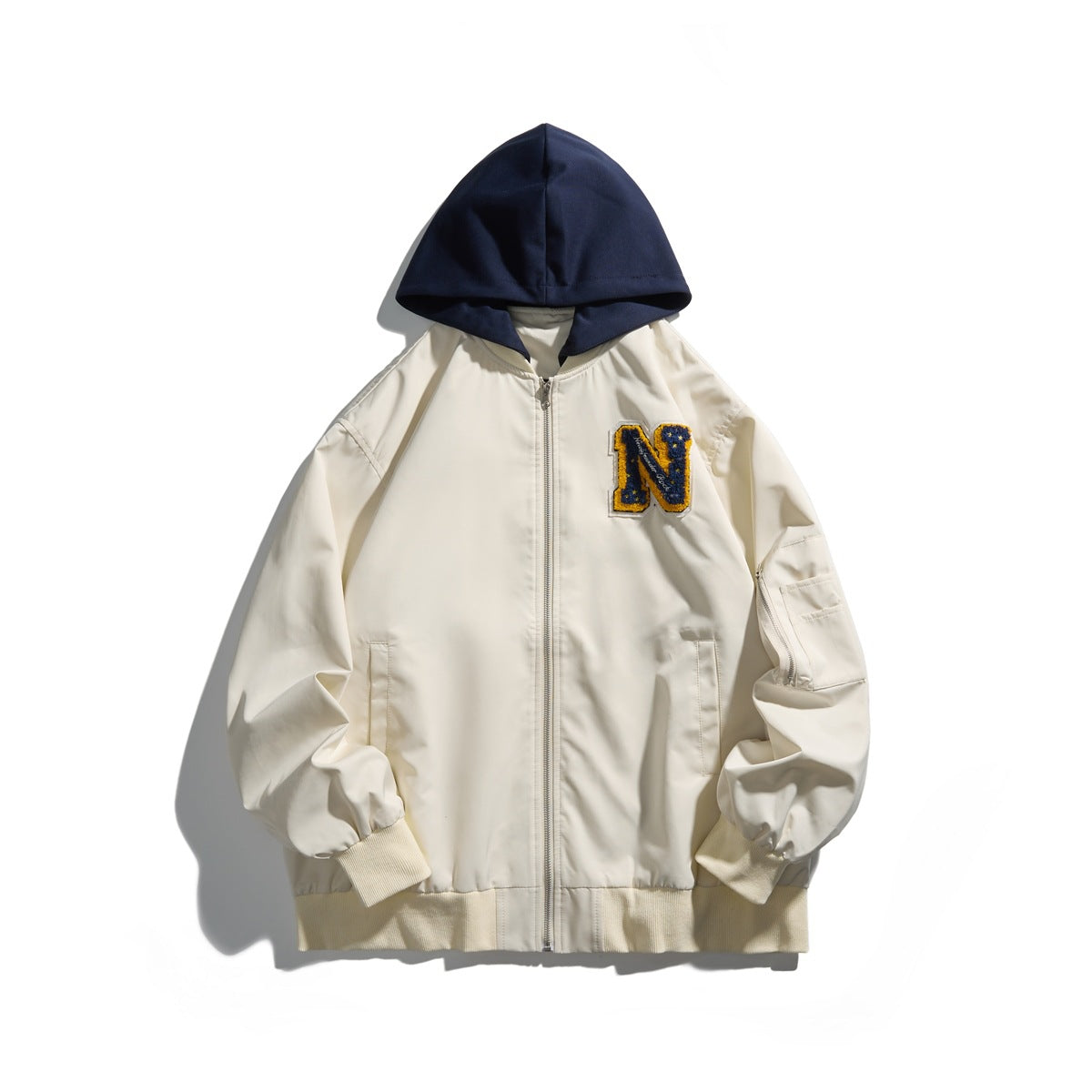 Front view of an ivory hooded zip-up jacket with a navy hood, ribbed cuffs and hem, and a blue-and-gold letter patch.