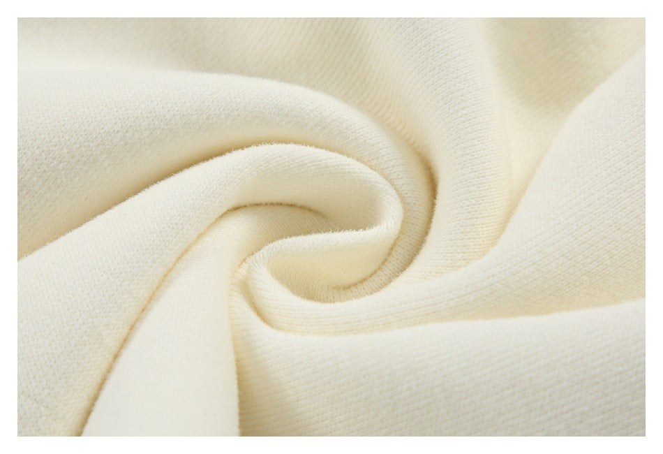 Close-up of soft-looking ivory knit fabric arranged in a spiral fold, revealing its fine texture.