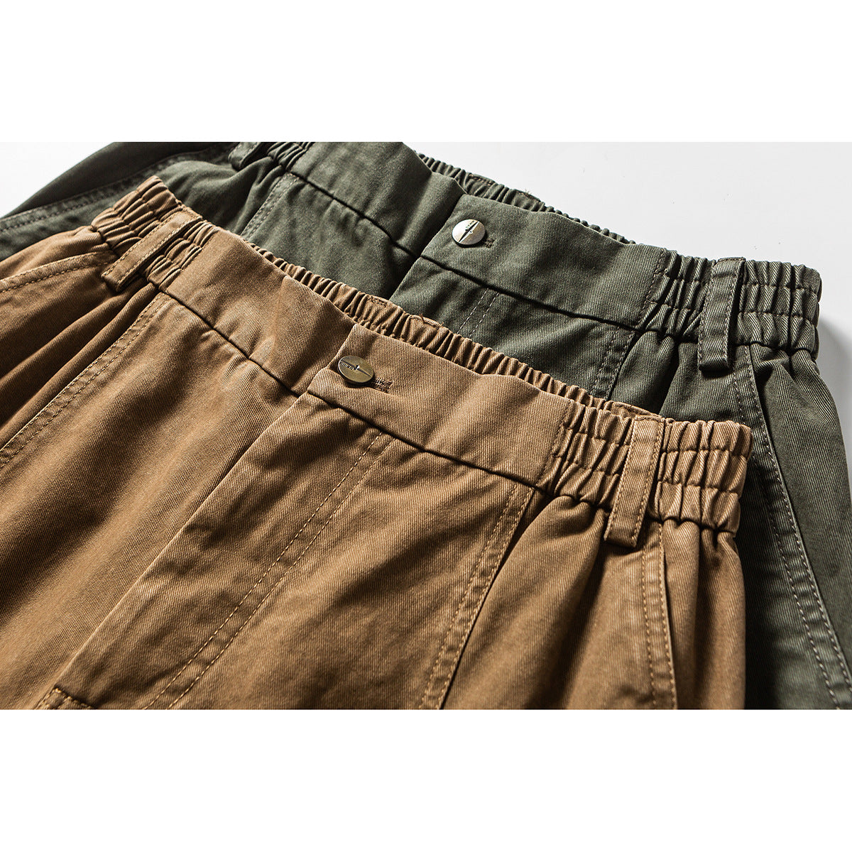 Close-up of olive and tan cargo pants showing elastic waistbands, buttons, belt loops and stitching.