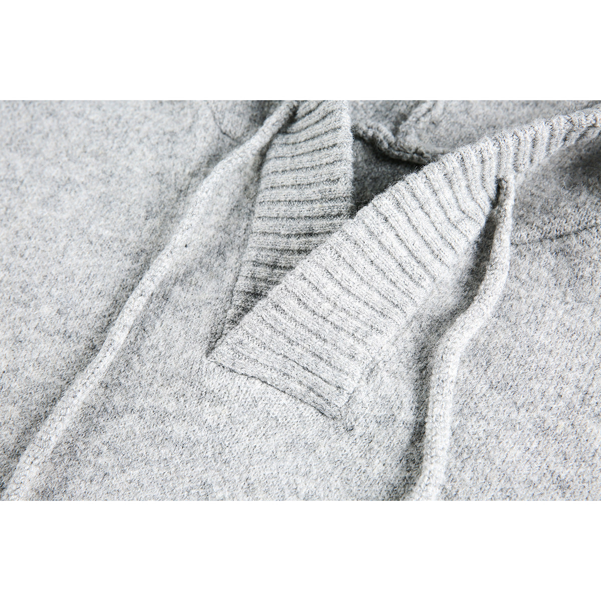 Close-up of a light gray sweater's ribbed neckline and front opening.