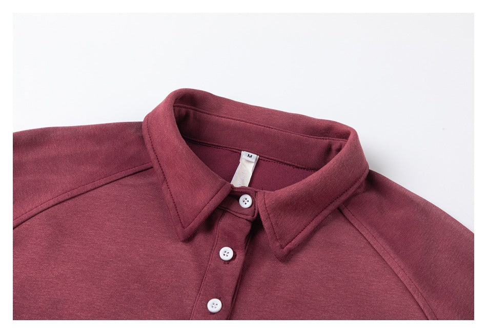 Close-up of the burgundy pullover's pointed collar, white buttons, raglan seams, and size M neck tag.