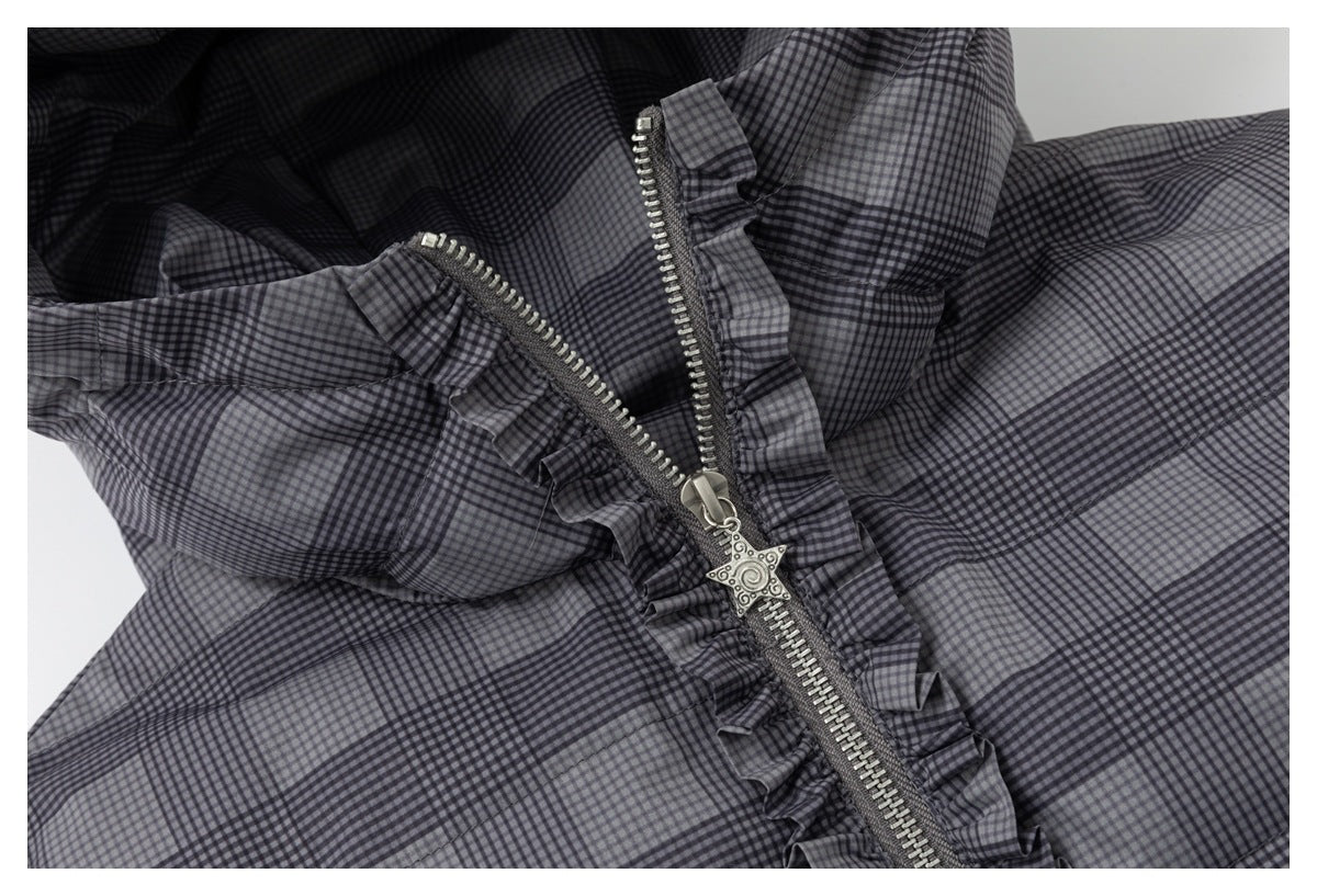 Close-up of the partially opened metal zipper and ruffled trim on a gray-and-black plaid jacket.