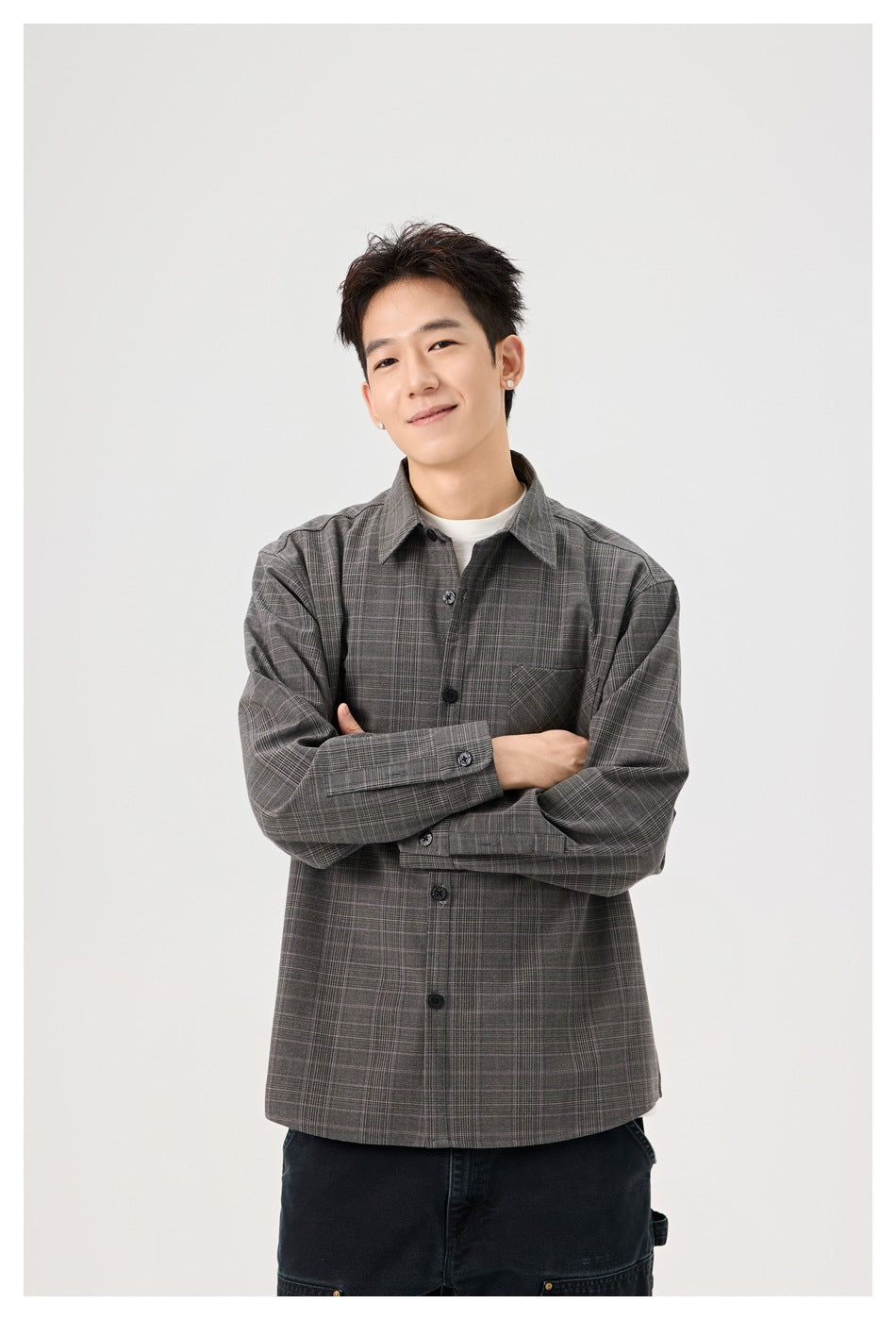 Model wearing a gray plaid button-up shirt over a white tee, arms crossed.