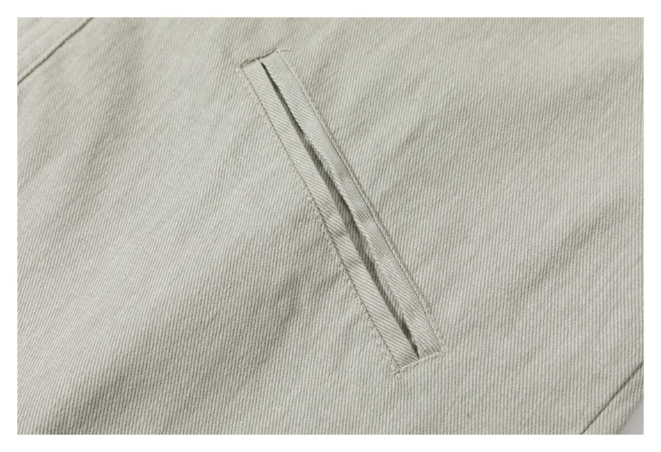 Close-up of a narrow slanted welt pocket on pale gray-beige fabric.