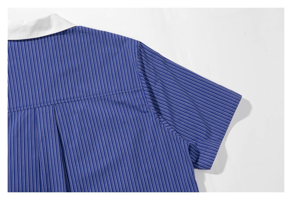 Close-up of the back yoke, white collar, and short sleeve of a blue vertically striped shirt.