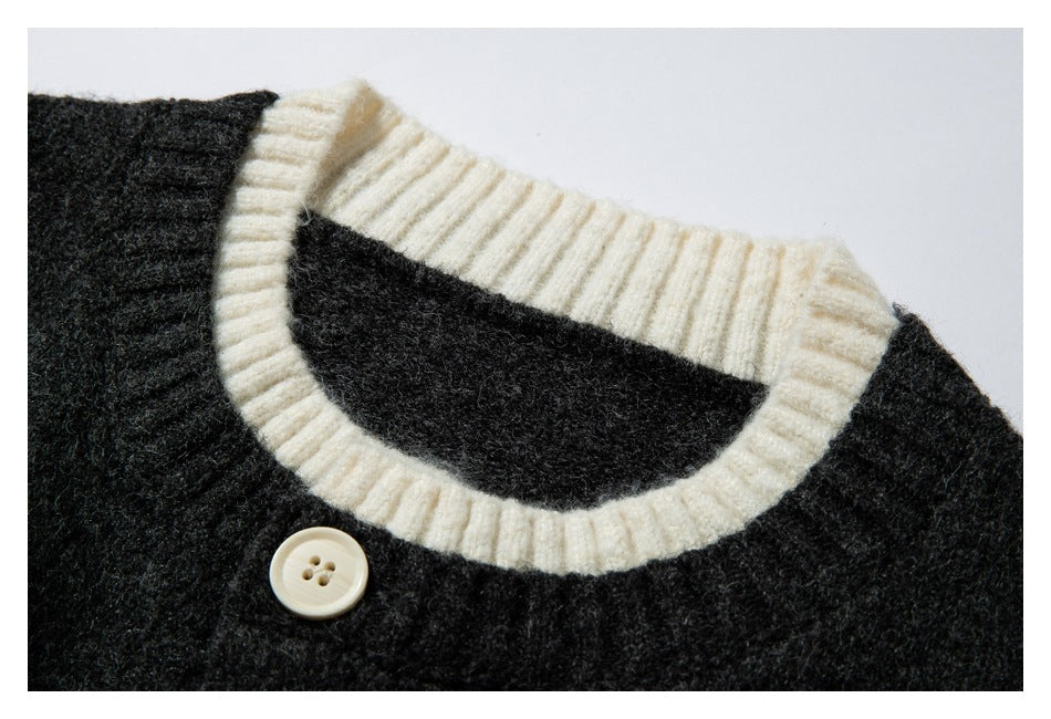 Close-up of a charcoal knit cardigan neckline with cream ribbed trim and a cream four-hole button.