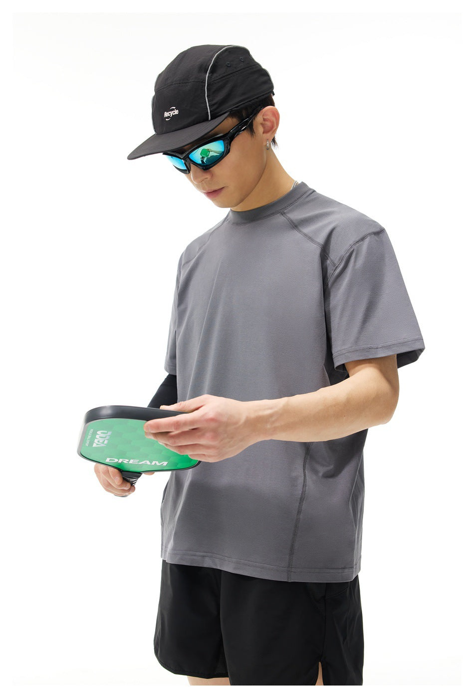 Model wearing a charcoal-gray short-sleeve shirt, shown at an angle while holding a green paddle.