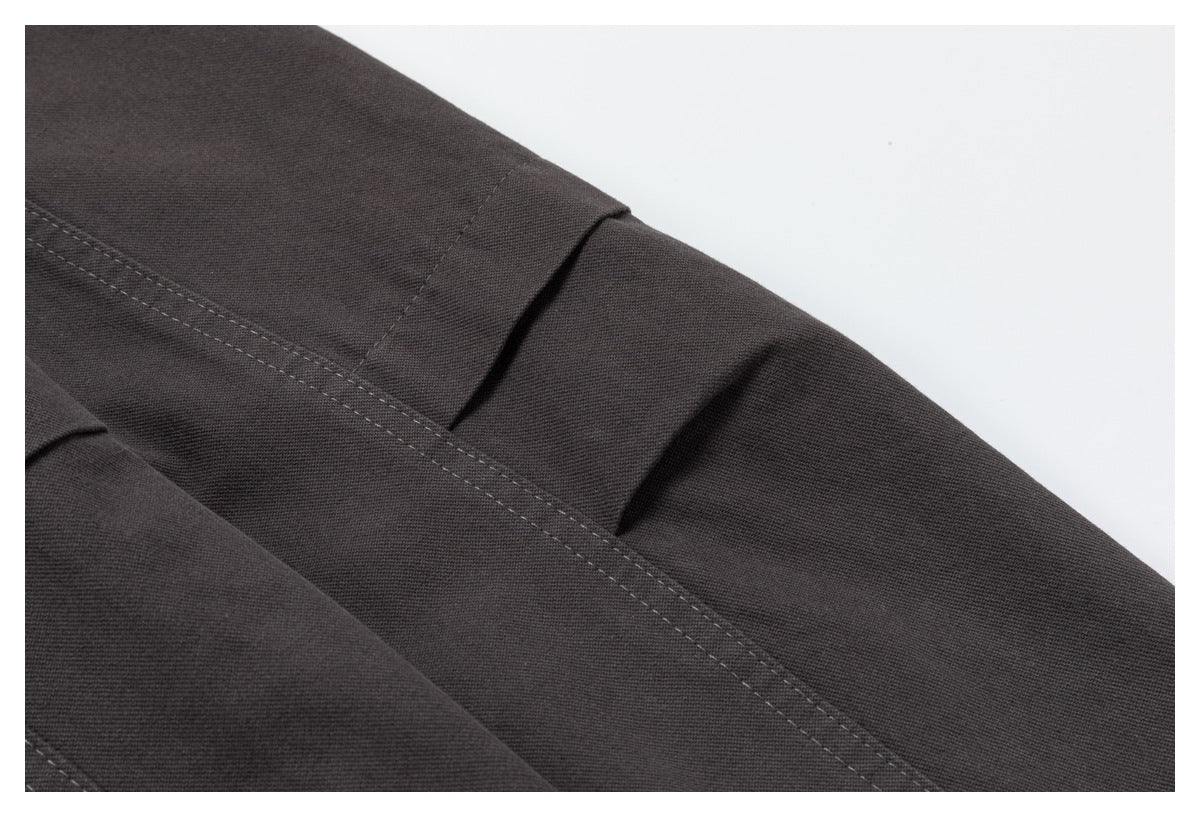 Close-up of dark charcoal jacket fabric with a folded seam and parallel topstitching.