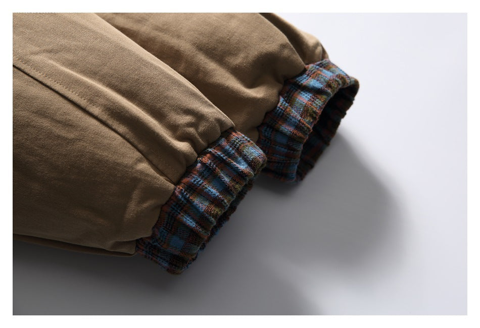 Close-up of tan jacket sleeves with gathered blue-brown plaid cuffs.