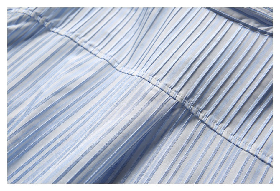 Close-up of the white shirt's blue-striped fabric and curved stitched seam.