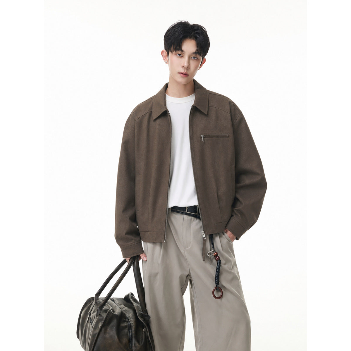 Model wearing a brown zip-front jacket with a pointed collar and horizontal chest zipper pocket.