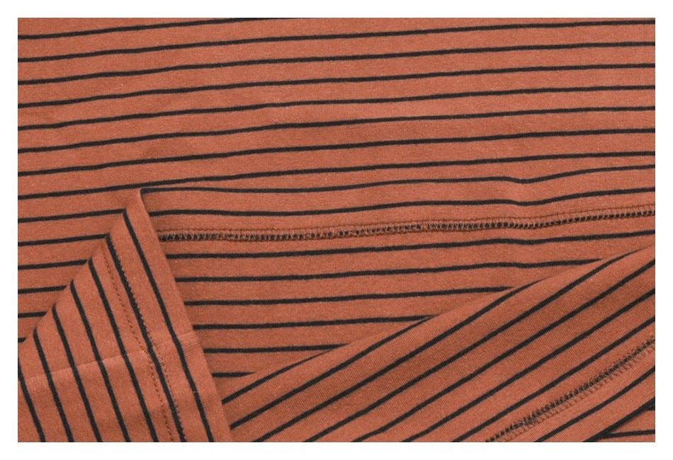 Close-up of striped rust-orange fabric showing a folded edge and stitched seam.