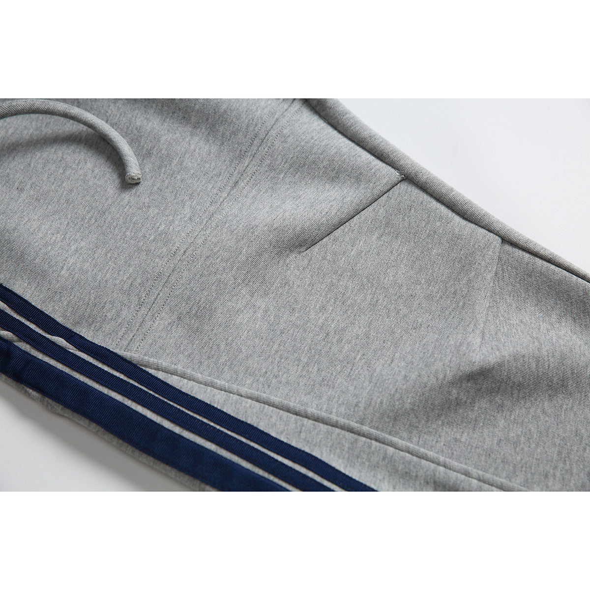 Close-up of gray jogger pants showing a side pocket, stitching, and navy-and-white stripes.