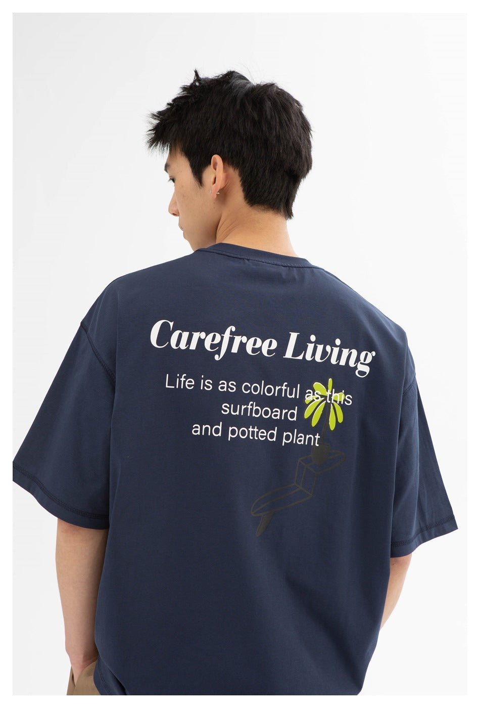 Close-up of the navy T-shirt's back print with white lettering and colorful plant and surfboard artwork.