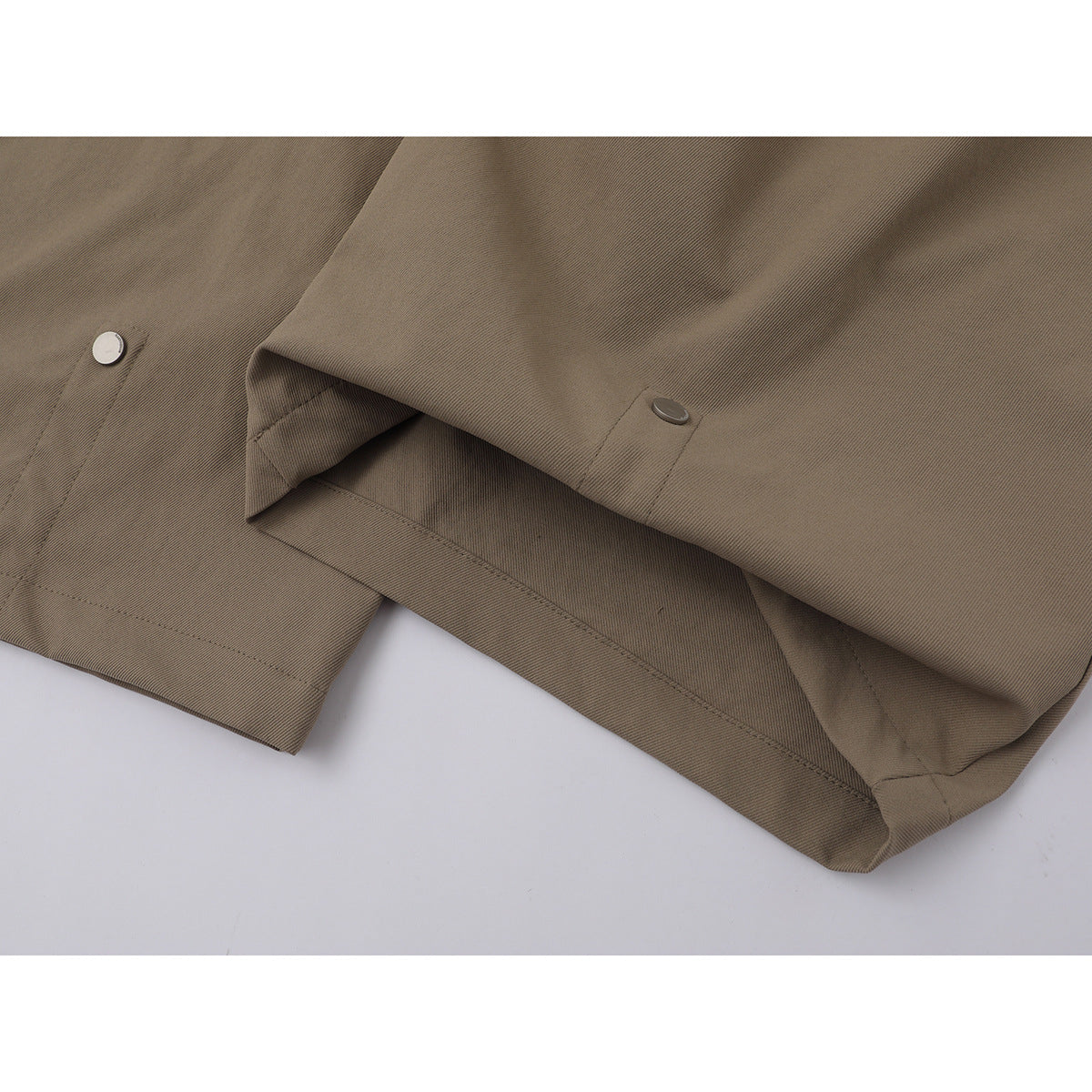 Close-up of taupe trouser legs and hems, with small snap fasteners visible.