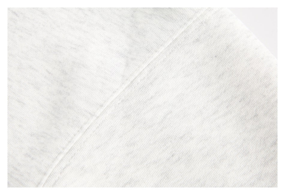 Extreme close-up of light heather gray hoodie fabric and a diagonal seam.