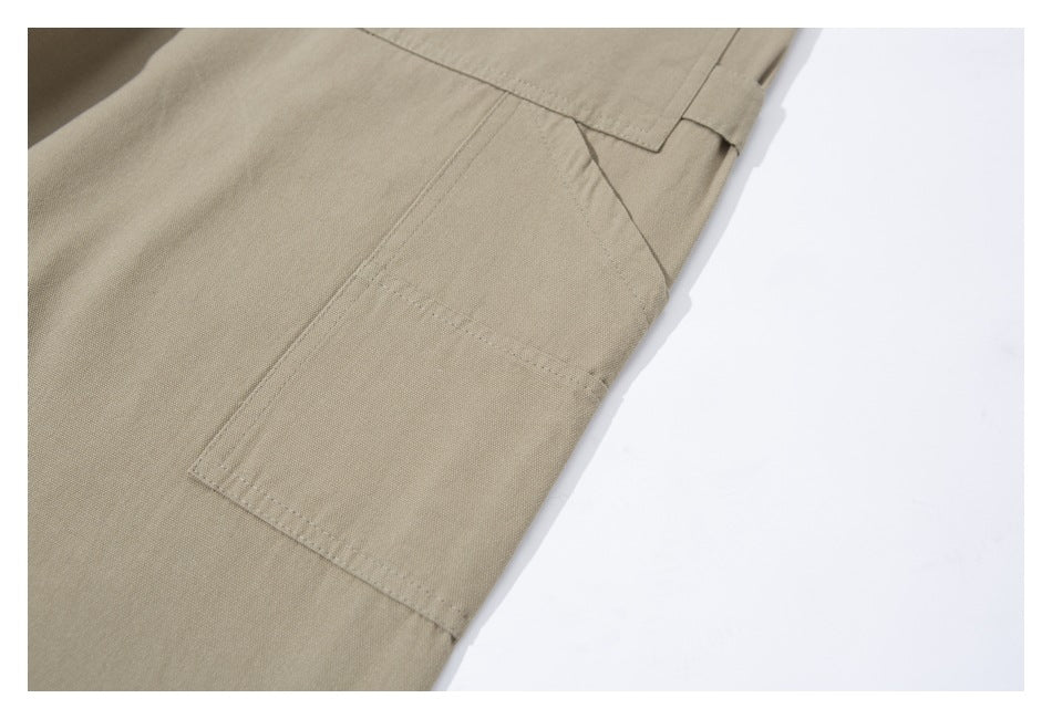 Close-up of beige trousers showing a stitched side cargo pocket and panel seams.