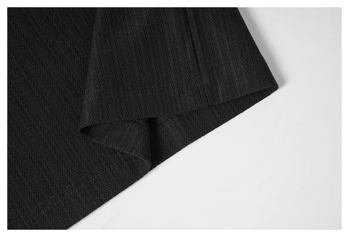 Close-up of the black textured shirt's hem and overlapping fabric edge.