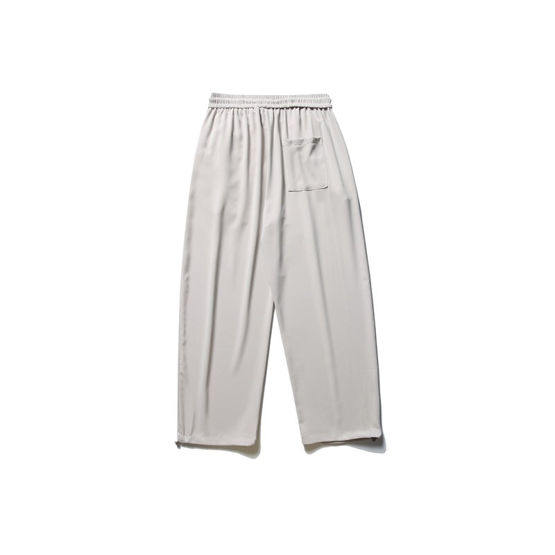 Light gray loose-fitting pants shown from the back, with an elastic waistband and a single patch pocket.