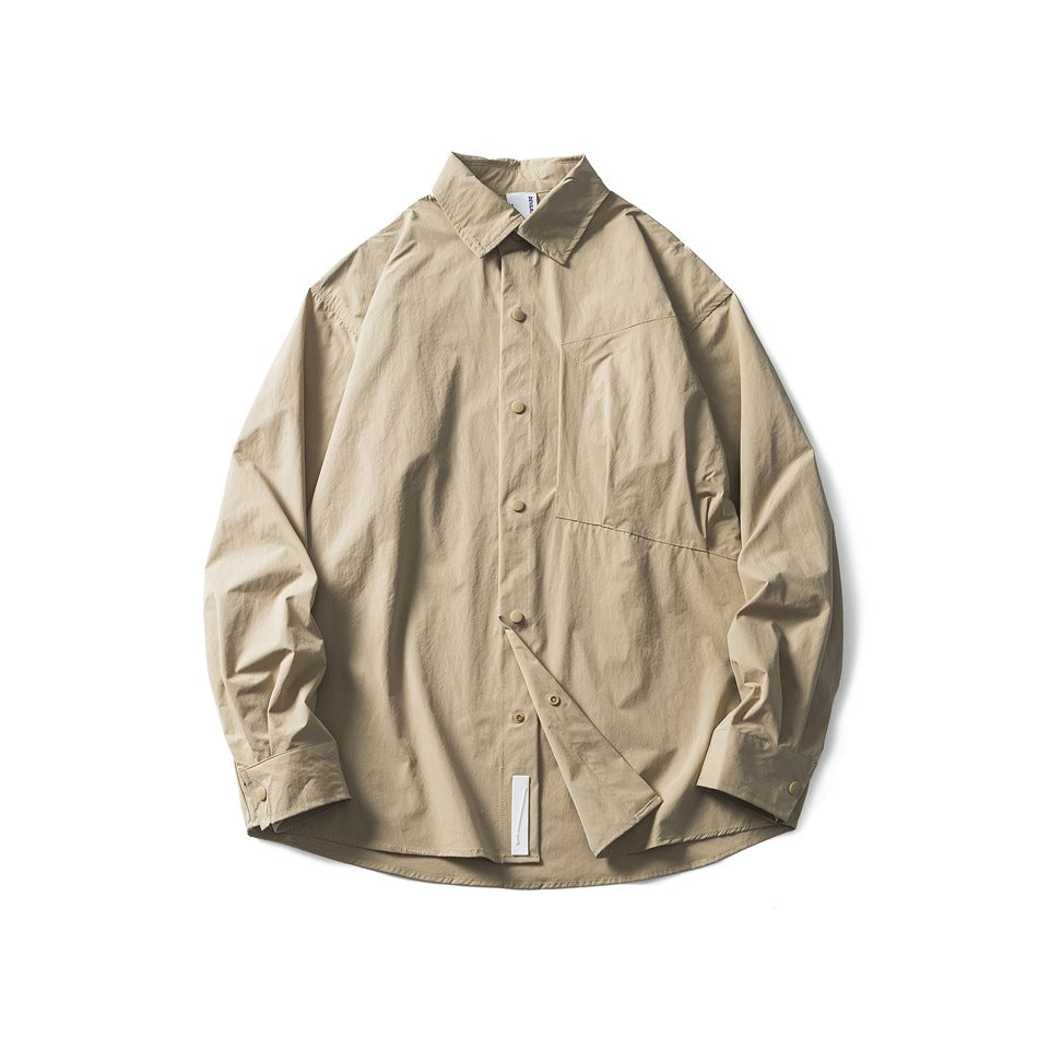 Khaki long-sleeve button-up shirt laid flat, showing collar, snap front, angled chest pocket and white tab