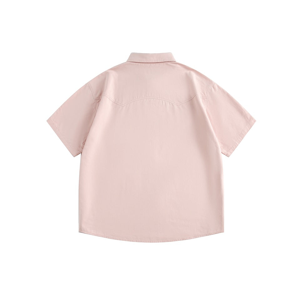 Back view of a pale pink short-sleeve button-up shirt with a curved yoke seam.