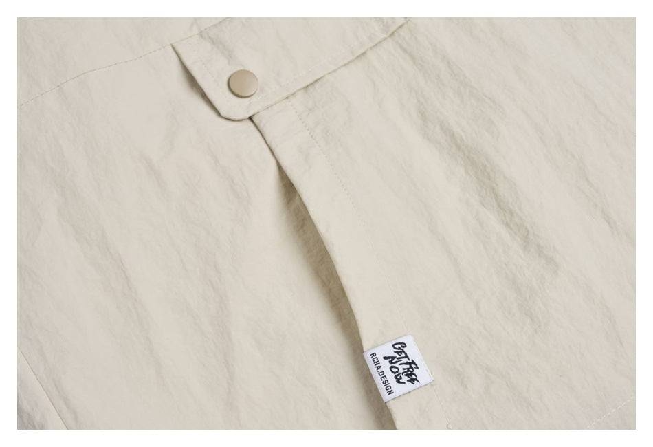 Close-up of ivory garment fabric, a beige snap button, and a small sewn-in label.