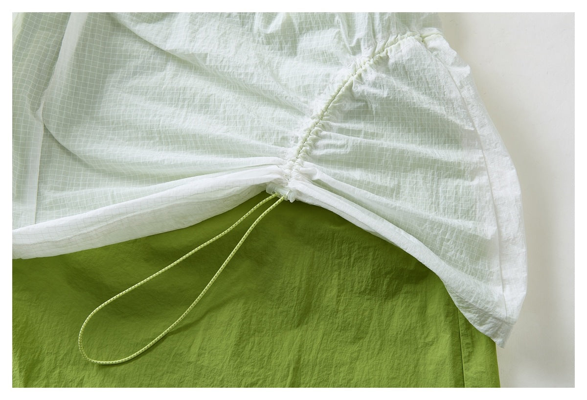 Close-up of a pale green grid-patterned skirt gathered at the hem with a lime drawcord over a solid green underlayer.