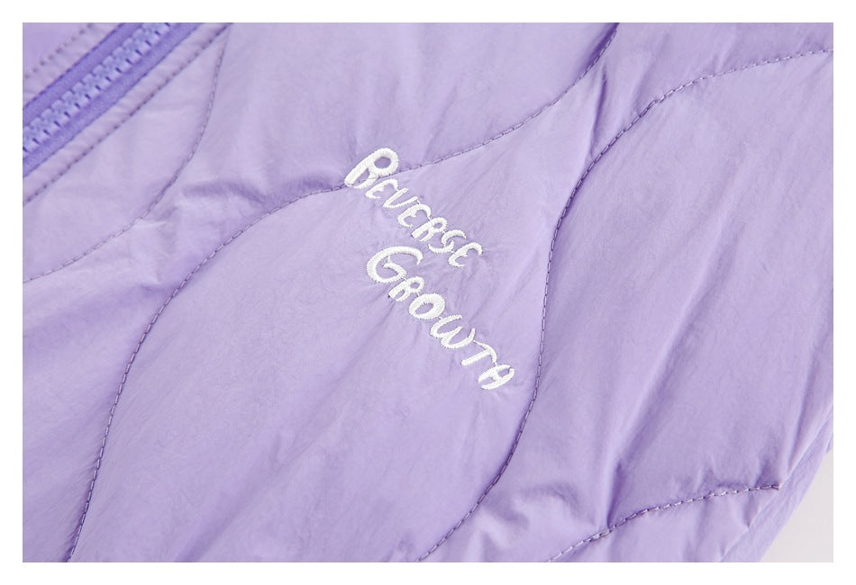 Close-up of white script embroidery on lavender quilted jacket fabric beside the zipper.