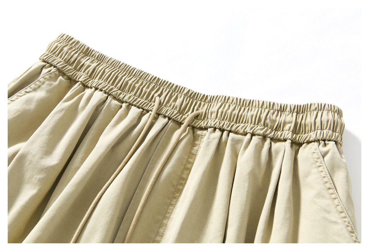 Close-up of beige trousers with a gathered elastic waistband and matching drawstrings.