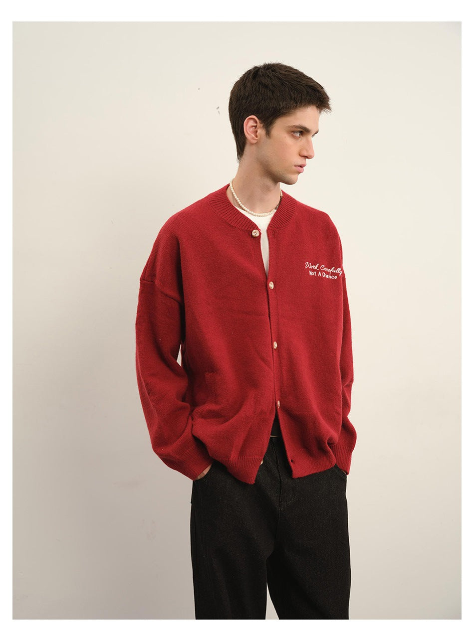 Model wearing a red button-front cardigan with white chest embroidery and black trousers.