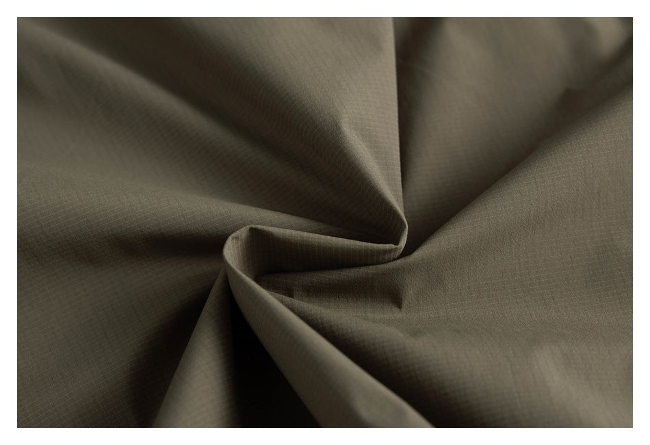 Close-up of olive-green fabric folded to show its subtle grid texture.